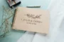 Customer holding personalised wooden wedding guest book from CluckingBelle showing engraved cover detail