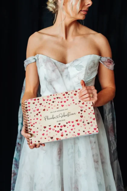 close-up of confetti hearts wooden wedding guest book cover showing engraved names and date