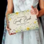 Yellow wildflower wedding guest book portrait cover personalised with bride name and wedding date on wooden surface