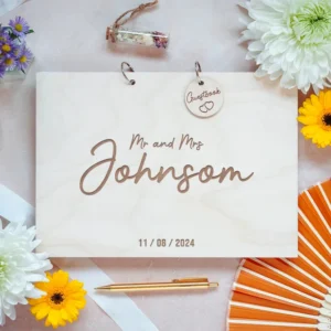 Personalised wooden wedding guest book with engraved couple names shown on a rustic wooden surface