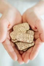 Personalised laser-engraved wooden wedding drink token showing art deco design with couple's names
