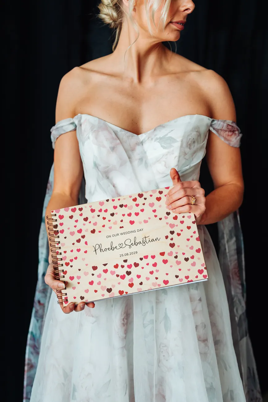 close-up of confetti hearts wooden wedding guest book cover showing engraved names and date