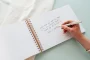 Open spiral-bound wooden wedding guest book showing Instax mini photos and guest messages on thick 160gsm white pages