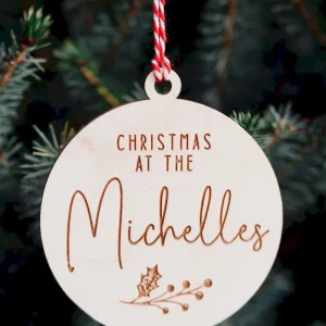 Home 16 Wooden family name Christmas bauble 'Christmas at the Michelles' with holly berries design hanging on a Christmas tree