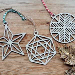 Home 8 Set of three geometric wooden Christmas baubles, star, hexagon and snowflake, on an oak table with gold leaves